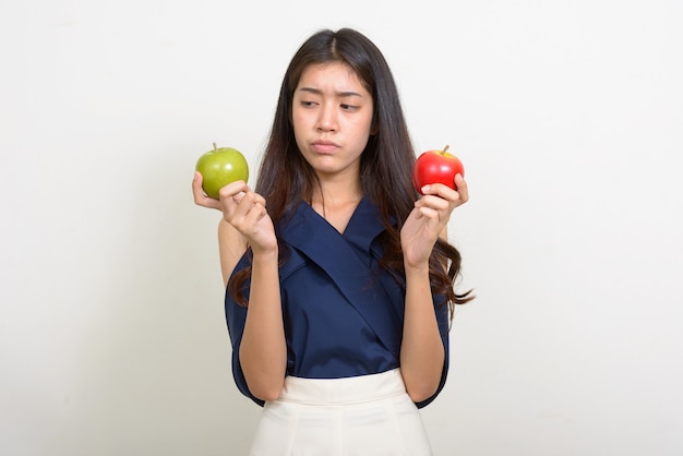 Portret van jonge mooie Aziatische onderneemster die tussen twee appels kiest