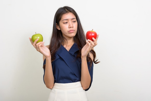 Portret van jonge mooie Aziatische onderneemster die tussen twee appels kiest