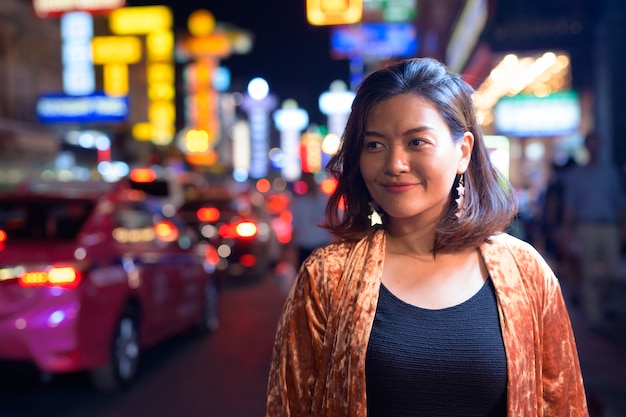 Portret van jonge mooie Aziatische toeristenvrouw die Chinatown in Bangkok onderzoekt