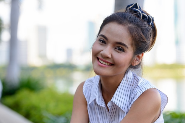 Portret van jonge mooie Aziatische toeristische vrouw ontspannen in het park buiten