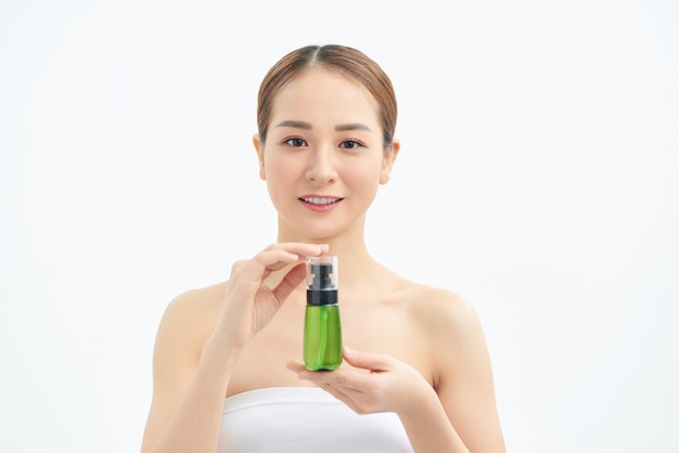 Portret van jonge mooie Aziatische vrouw die cosmetische product groene fles bij de hand toont.