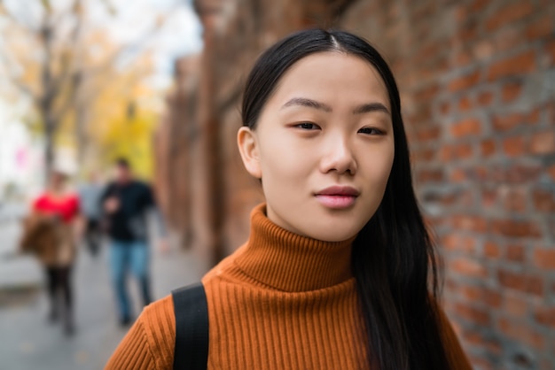 Portret van jonge mooie Aziatische vrouw die zich buiten in de straat bevindt.