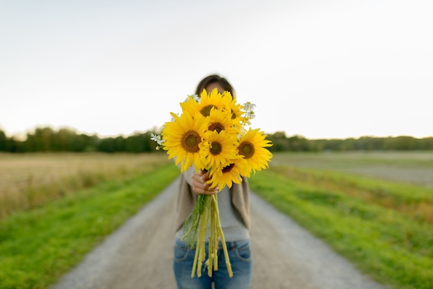 Portret van jonge mooie Aziatische vrouw op het gebied van bloeiende zonnebloemen buiten