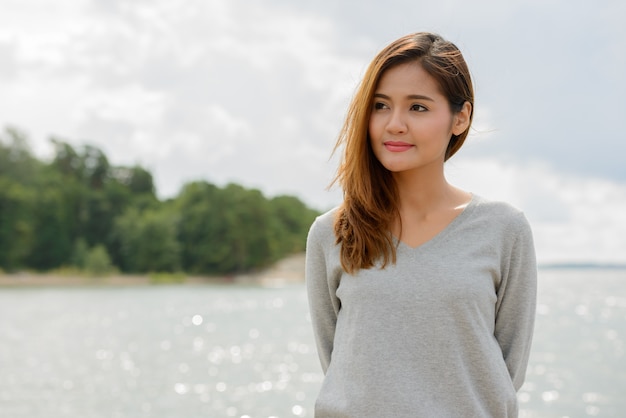 Portret van jonge mooie Aziatische vrouw tegen schilderachtig uitzicht op het meer en de lucht in de natuur