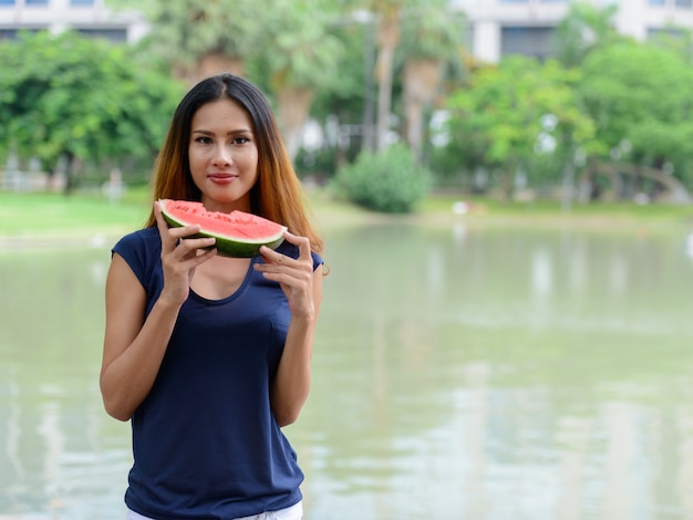 Portret van jonge mooie Aziatische zakenvrouw ontspannen in het park buiten