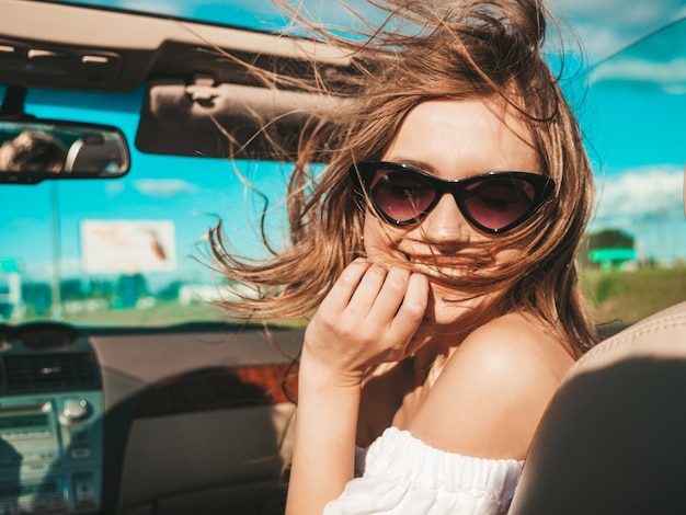 Portret van jonge mooie en lachende hipster vrouw in converteerbare auto