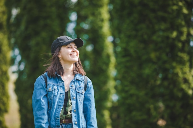 Portret van jonge mooie lachende vrouw in cap groene bomen op background