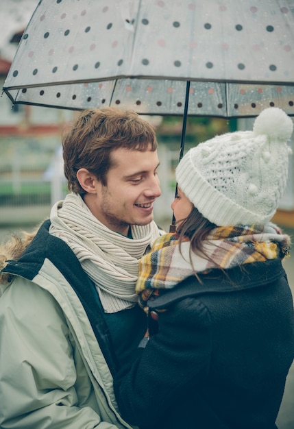 Portret van jonge mooie paar omarmen onder de paraplu in een regenachtige herfstdag. Liefde en paar relaties concept.