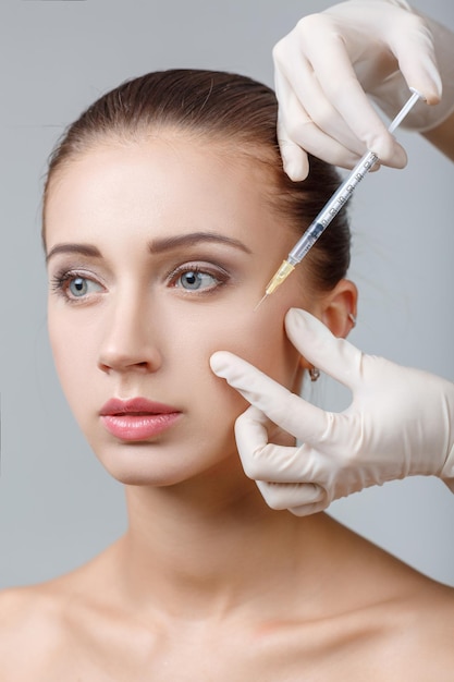 Portret van jonge mooie vrouw die cosmetische opheffing injectie in het gezicht krijgt. Plastische chirurgie. Cosmetische behandeling