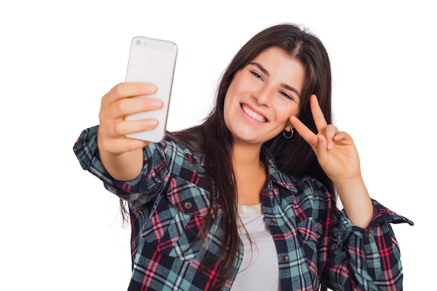 Portret van jonge mooie vrouw die een selfie met haar mobiele telefoon neemt die in een studio wordt geïsoleerd.