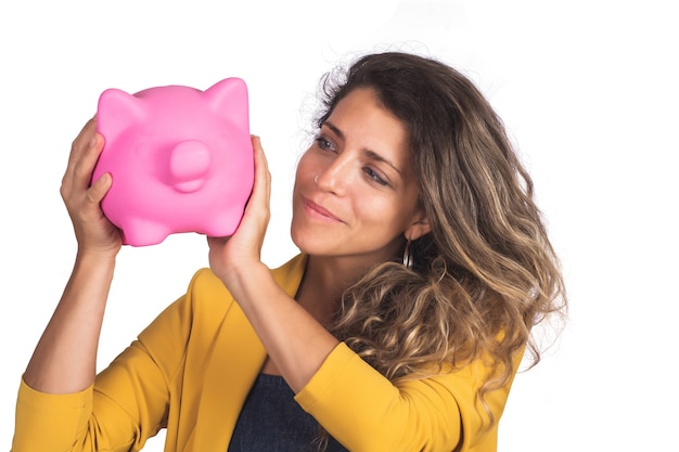 Portret van jonge mooie vrouw die een spaarvarken op studio houdt. Geïsoleerde witte achtergrond. Bespaar geld concept.