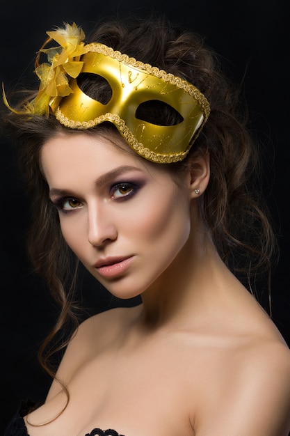 Portret van jonge mooie vrouw die gouden partijmasker draagt