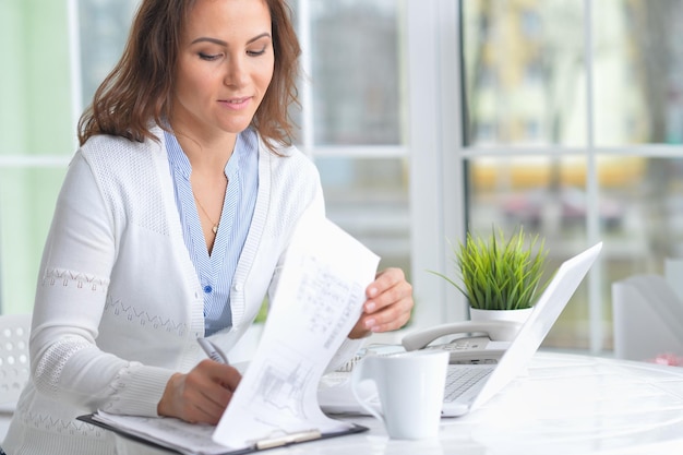 Portret van jonge mooie vrouw die met laptop werkt