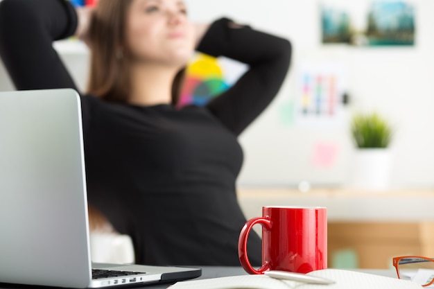 Portret van jonge mooie vrouw het drinken van thee tijdens het werken