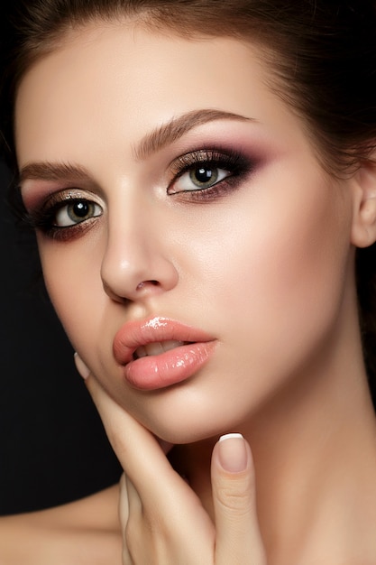 Portret van jonge mooie vrouw met avond make-up wat betreft haar gezicht op zwarte achtergrond.