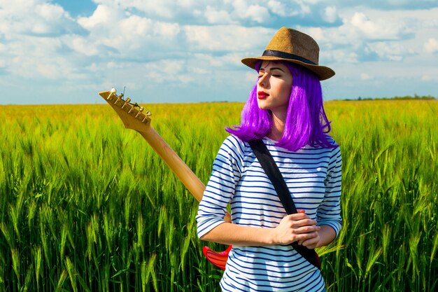 Portret van jonge mooie vrouw met elektrische gitaar in het veld