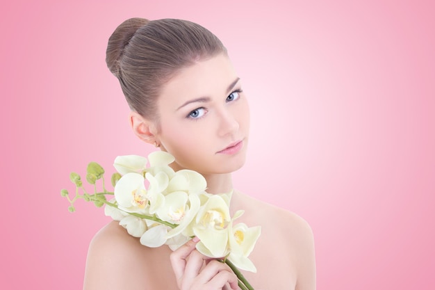 Portret van jonge mooie vrouw met orchideebloem over roze background