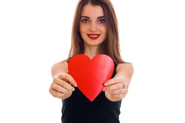 Portret van jonge mooie vrouw met rood hart dat op witte muur wordt geïsoleerd