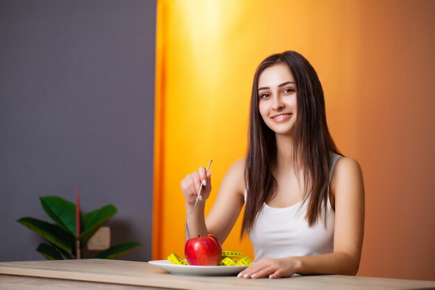 Portret van jonge mooie vrouw met tomaat en meetlint op plaat