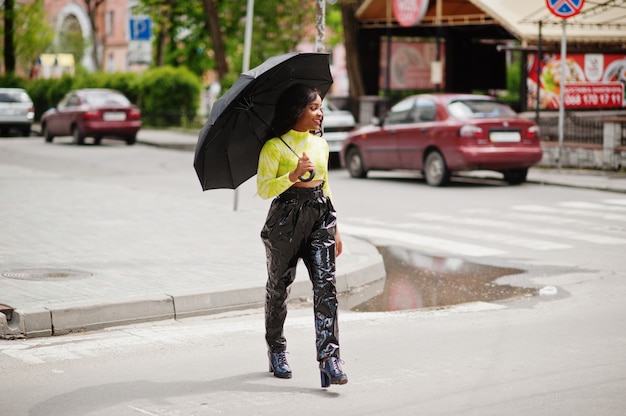 Portret van jonge mooie vrouw met zwarte paraplu en wandelende oversteekplaats