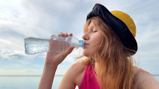 Foto portret van jonge mooie vrouw mineraalwater drinken uit plastic fles op zomerdag