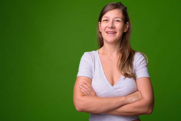 Portret van jonge mooie vrouw tegen groene muur