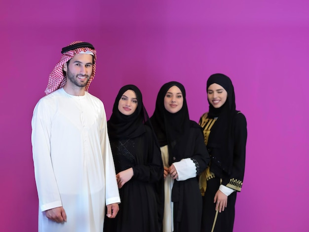 Portret van jonge moslimmensen in traditionele kleding. Gelukkige Arabische familie samen, man en drie vrouwen geïsoleerd op roze achtergrond