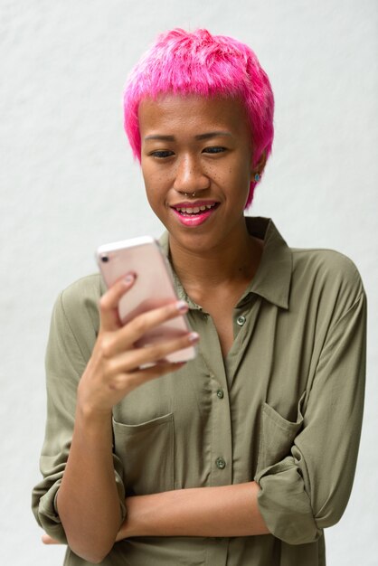 Portret van jonge opstandige Aziatische vrouw met roze haar tegen witte ruimte