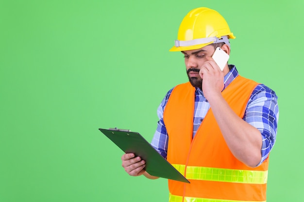 Portret van jonge overgewicht bebaarde Indiase man bouwvakker tegen Chromakey met groene muur