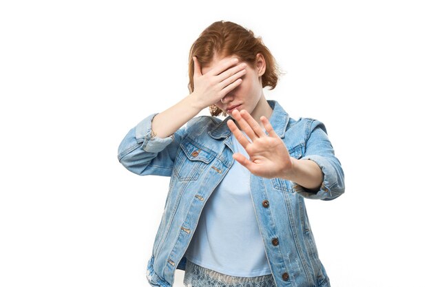 Portret van jonge roodharige vrouw met stopbord met hand geïsoleerd op een witte achtergrond