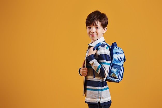 Portret van jonge slimme schooler in de studio tegen gele achtergrond.