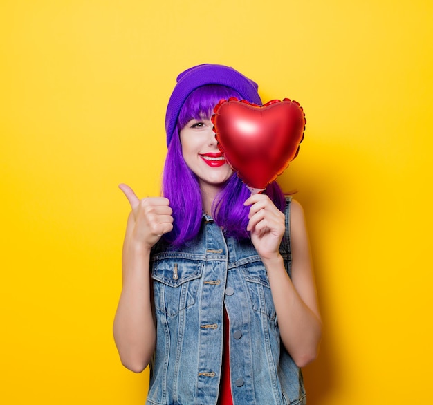 Portret van jonge stijl hipster meisje met paars haar en hart vorm ballon op gele achtergrond. St. Valentijnsdag vakantie