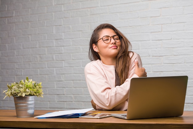 Portret van jonge student Latijns-vrouw zittend op haar bureau trots en vol vertrouwen