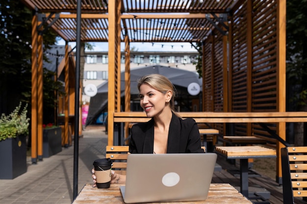 Portret van jonge succesvolle vrouw met laptop buitenshuis