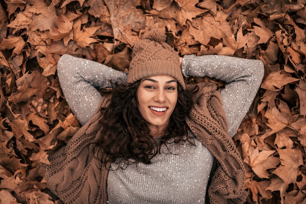 Portret van jonge toevallige donkerbruine vrouw die op de herfstgrond ligt. Bovenaanzicht.