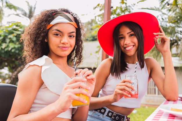 Portret van jonge vrienden die sap drinken. Twee donkerbruine vrienden die van een zomerdag genieten. Zomer en vriendschap concept.