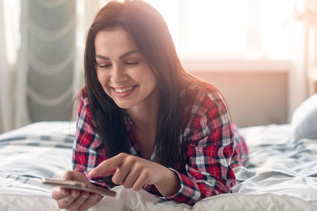 Foto portret van jonge vrouw die mobiele telefoon doorbladert