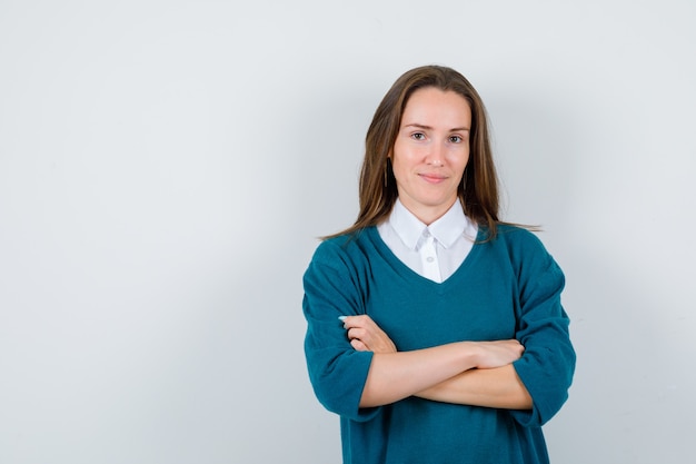 Portret van jonge vrouw met armen gevouwen in trui over shirt en zelfverzekerd vooraanzicht