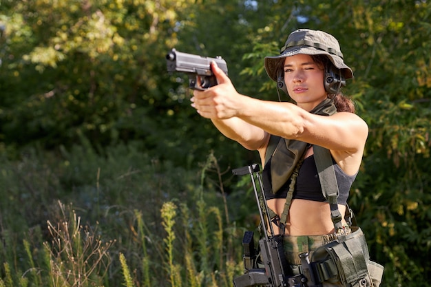 Portret van jonge vrouw met wapen in militaire slijtage buitenshuis