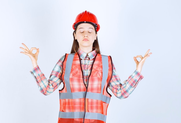 Foto portret van jonge vrouwelijke ingenieur in helm die duimen opgeeft.