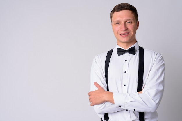 Portret van jonge zakenman bretels dragen tegen witte muur