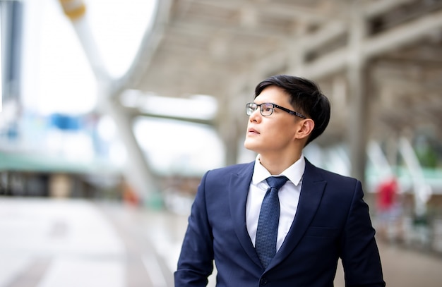 Portret van jonge zakenman met arm kruis tegen wazig gebouw