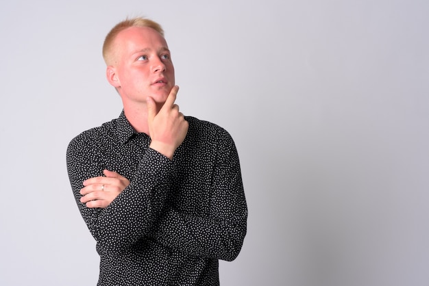 Portret van jonge zakenman met blond haar tegen witte muur