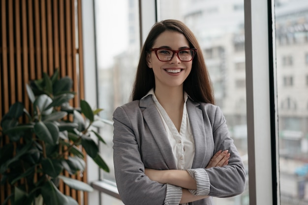 Portret van jonge zekere onderneemster met gekruiste wapens status in bureau