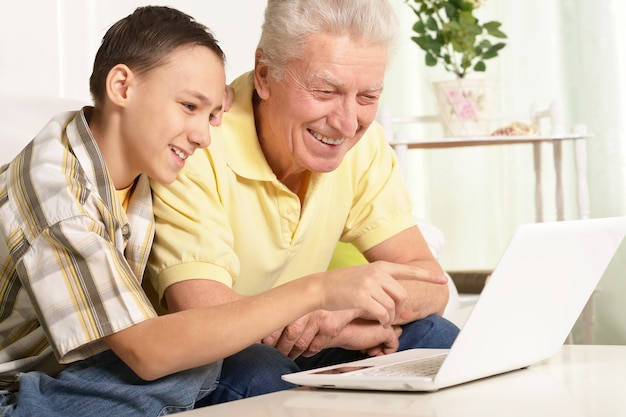 portret van jongen en grootvader met een laptop thuis