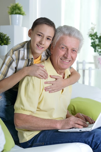 Portret van jongen en grootvader met een laptop thuis