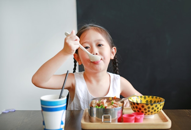 Portret van klein Aziatisch kindmeisje die ontbijt hebben bij de ochtend.
