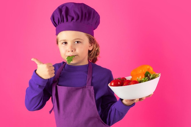 Portret van klein kind in uniform van kok Chef-kok jongen geïsoleerd op studio achtergrond Schattig kind om chef-kok te zijn