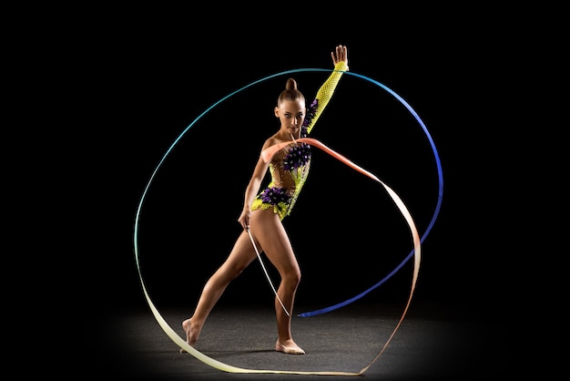 Portret van klein meisje, ritmische gymnastiek kunstenaar opleiding geïsoleerd op dark