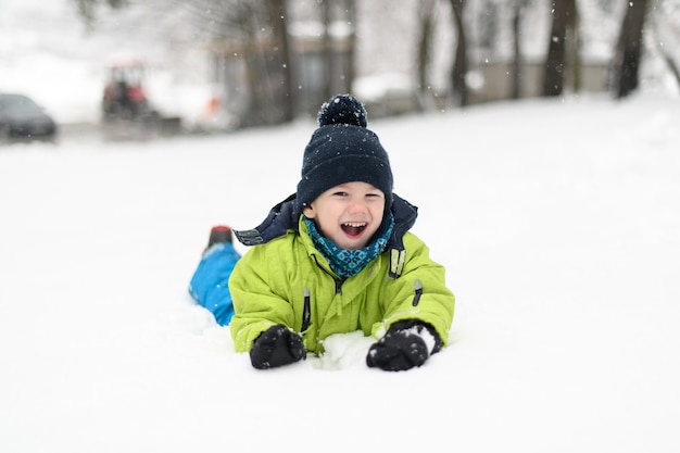 Foto portret van kleine gelukkige jongen ligt in de sneeuw